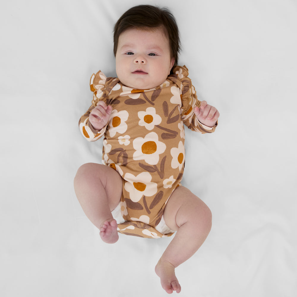 Infant lying down wearing a Daisy Daydream flutter baby bodysuit