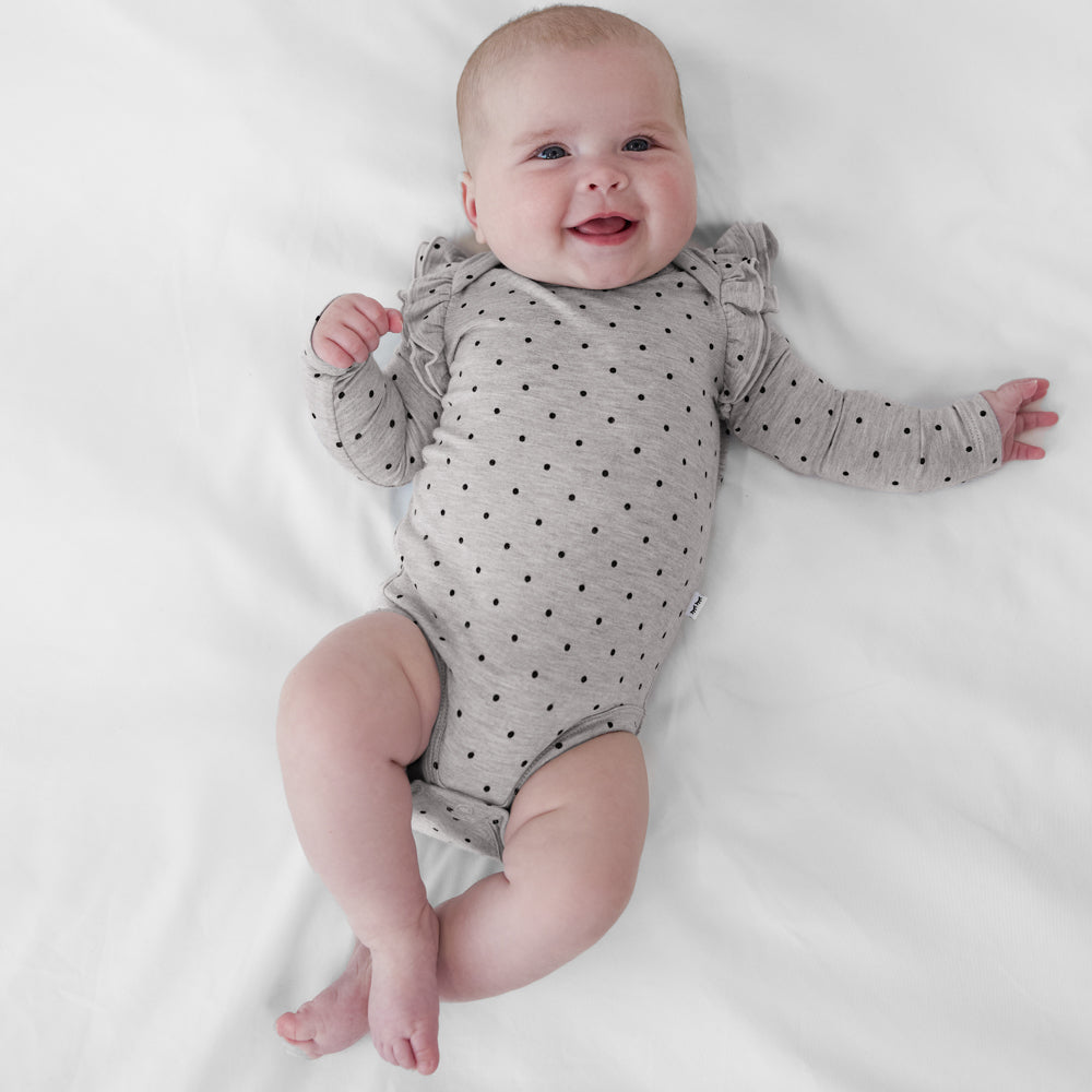 Infant lying on a blanket wearing a Ditsy Dots long sleeve flutter baby bodysuit