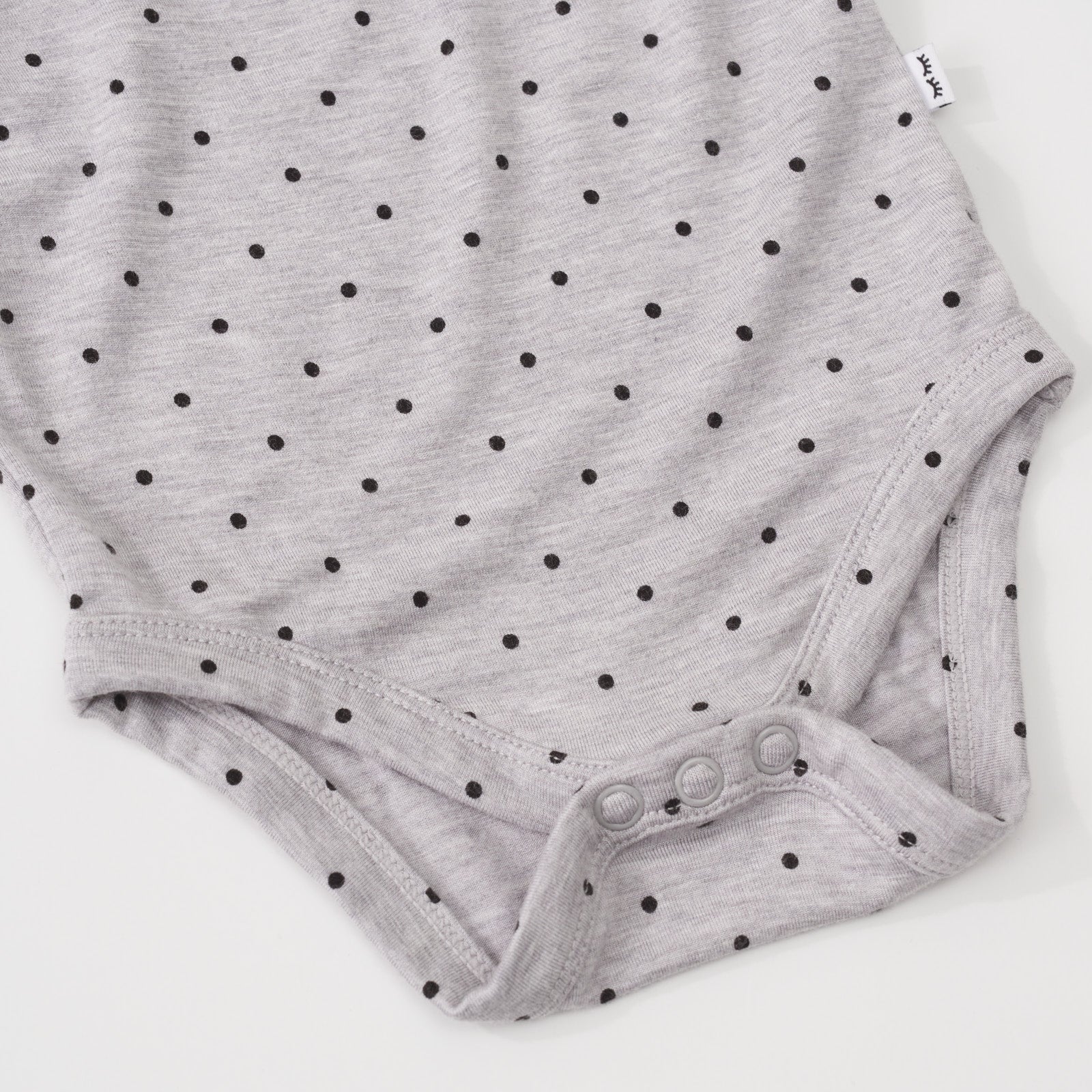 Close-up view of the button snap closure on a Ditsy Dots flutter baby bodysuit