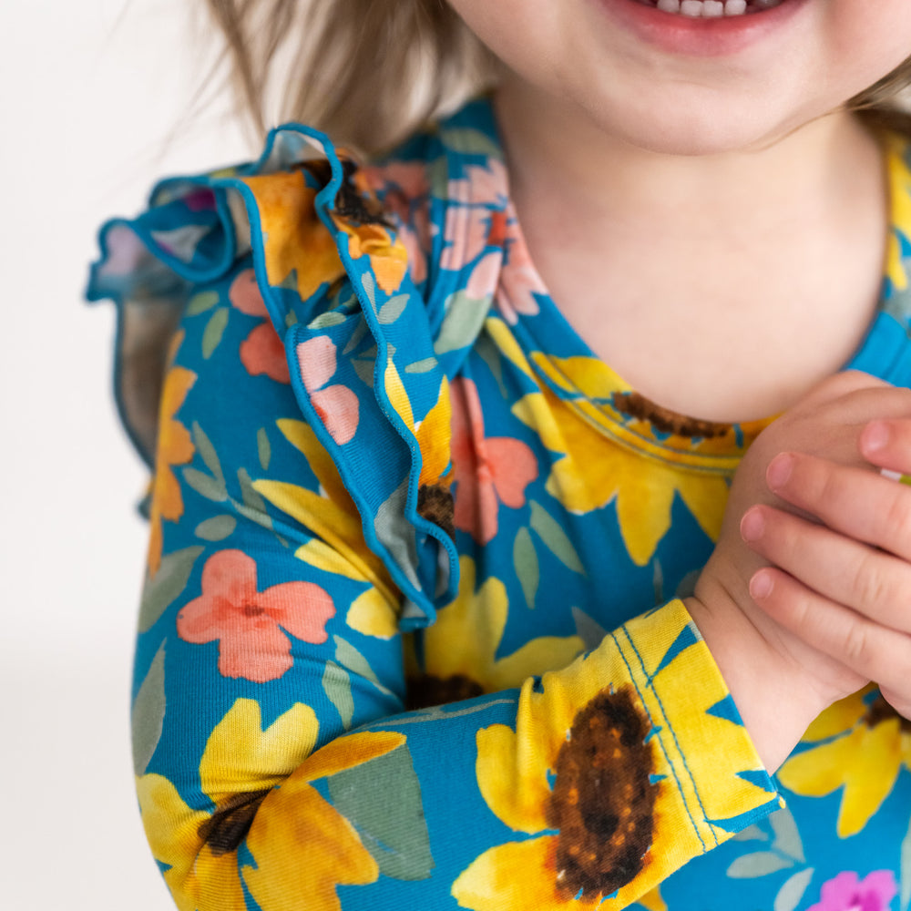 Close up image of a child wearing a Sunflower Fields Flutter Bodysuit, detailing the flutter sleeve