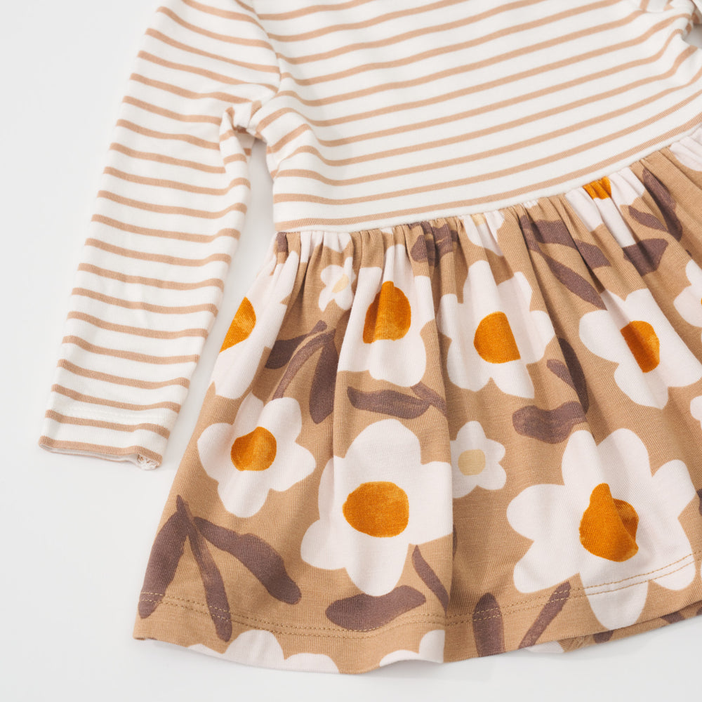 Close up view of the tan stripes top pattern and tan floral skirt pattern on a Daisy Daydream twirl dress