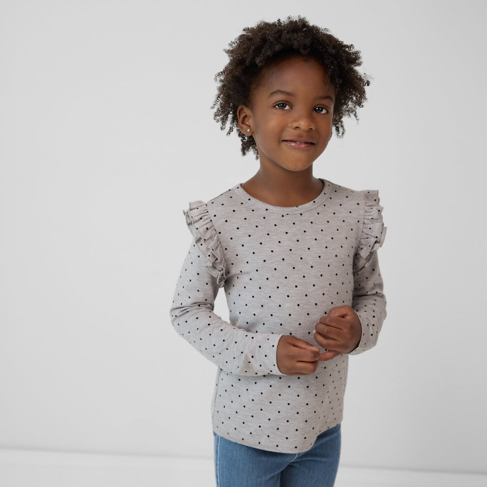 Child holding her hands wearing a Ditsy Dots flutter tee paired with denim jeggings