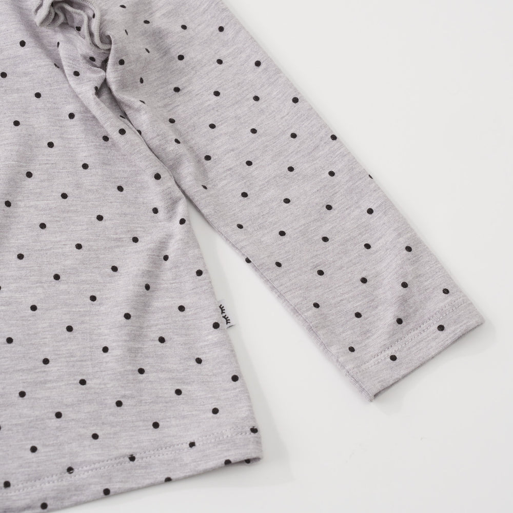 Close-up view of the black dots pattern on a Ditsy Dots long sleeve flutter tee