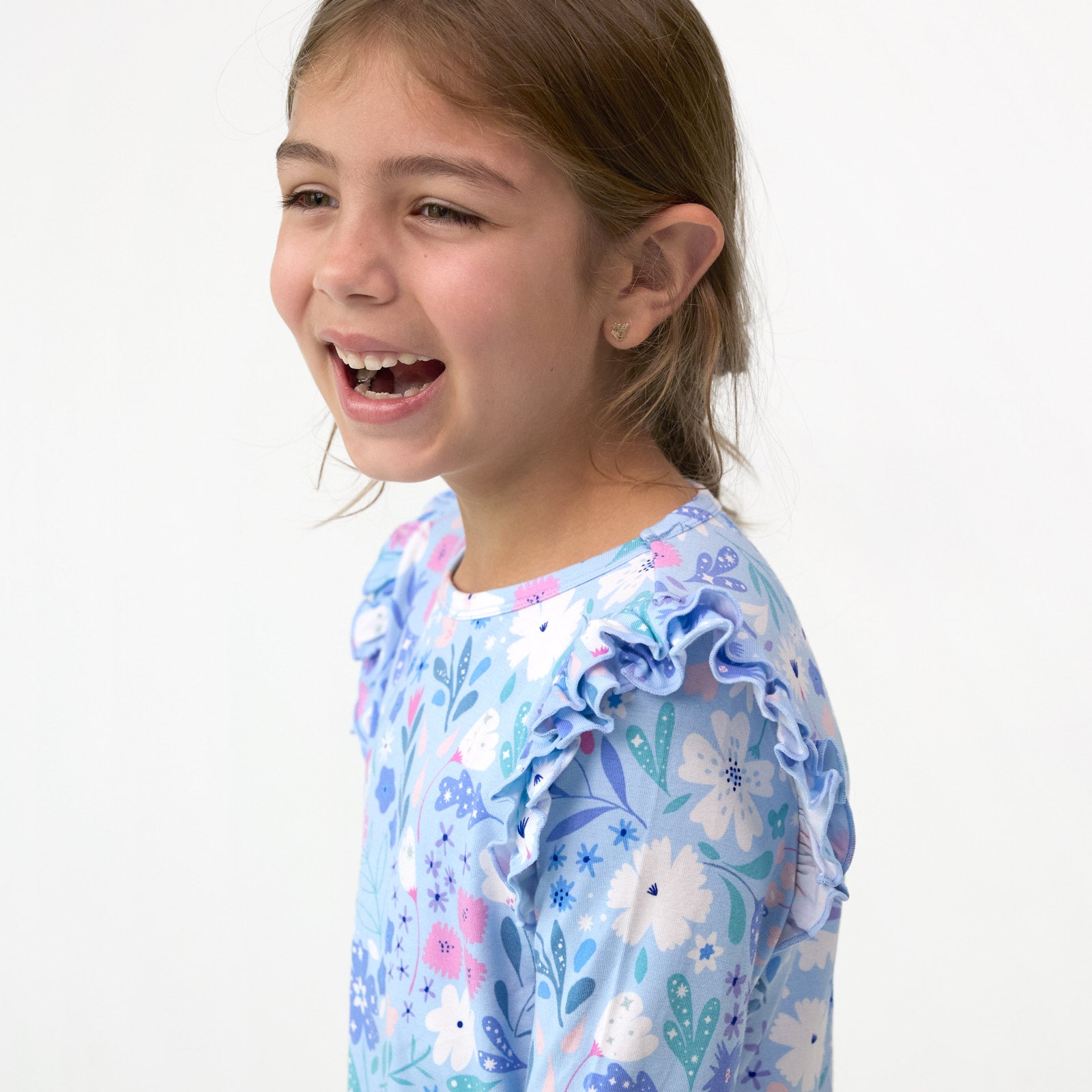 Close up image of girl laughing while displaying the flutter should detail on the Magical Meadow Flutter Tee