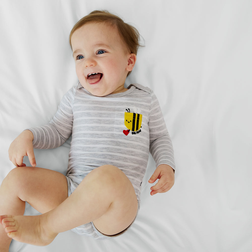 infant lying on a white blanket wearing a bee mine pocket bodysuit