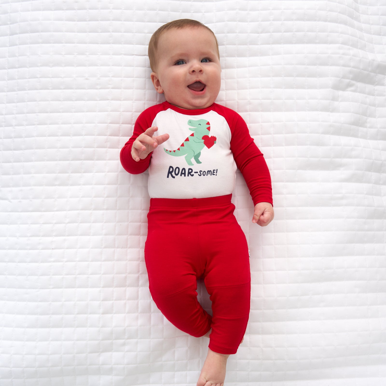 Child laying on a blanket wearing Candy Red leggings and a coordinating bodysuit