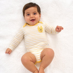 Child laying on a blanket wearing a Disney Winnie the Pooh graphic pocket bodysuit