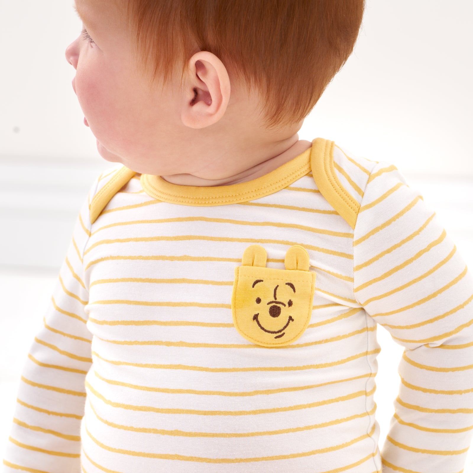 Close up image of a child wearing a Disney Winnie the Pooh graphic pocket bodysuit detailing the pocket