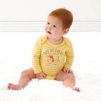 Child sitting on a blanket wearing a Disney Winnie the Pooh graphic bodysuit