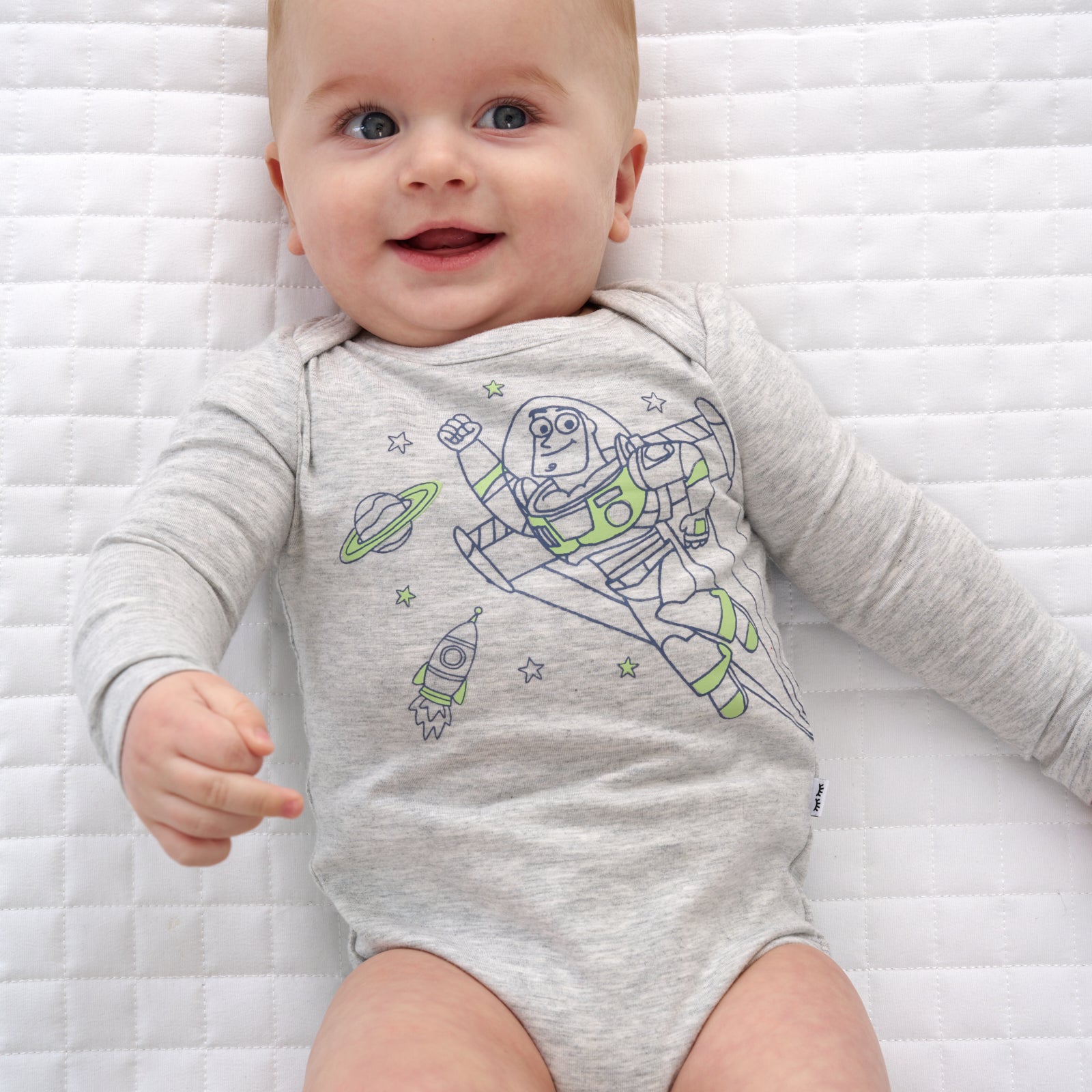 Close up image of a child laying on a blanket wearing a Disney Pixar Buzz Lightyear Graphic Bodysuit