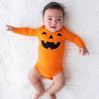 Top view image baby laying down in the Jack-O'-Lantern Graphic Bodysuit