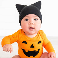 Close up image of baby wearing the Jack-O'-Lantern Graphic Bodysuit & Cat Ears Infant Hat 