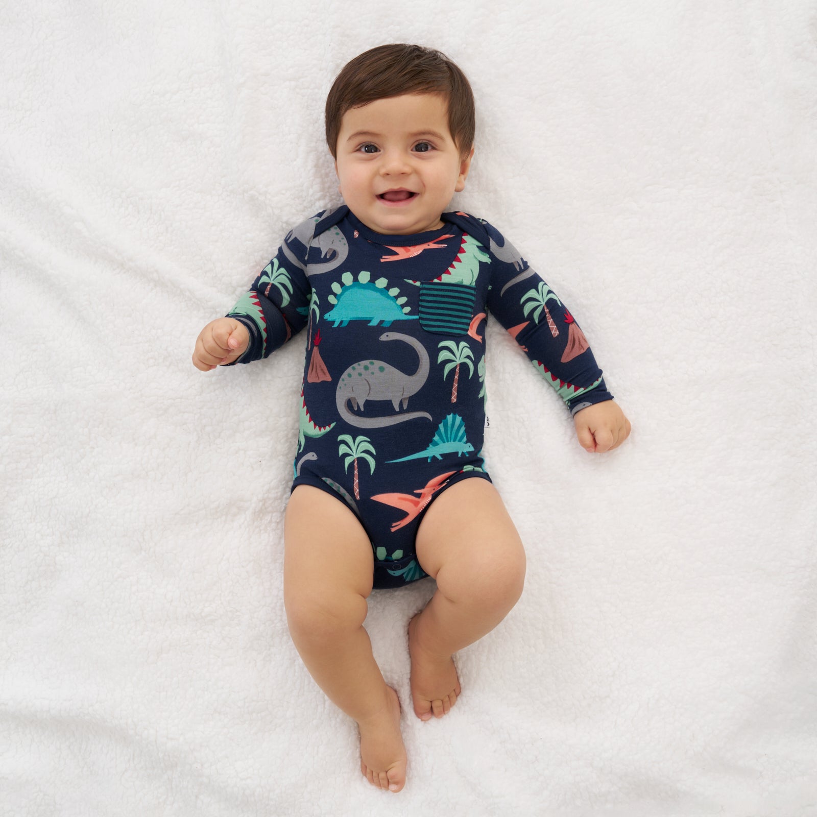 Child laying on a blanket wearing a Blue Prehistoric Pals pocket bodysuit