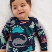 Close up image of a child laying on a blanket wearing a Blue Prehistoric Pals pocket bodysuit