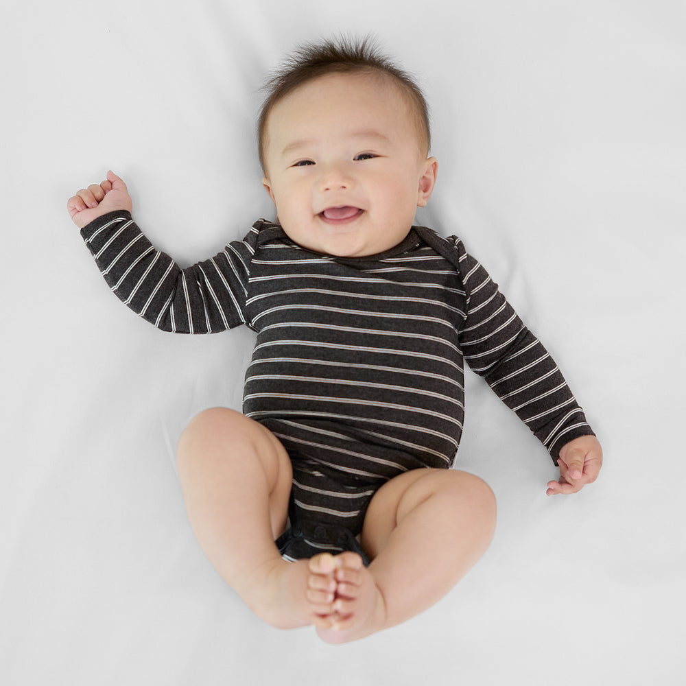 Infant lying down wearing a Heather Black Stripes long sleeve baby bodysuit