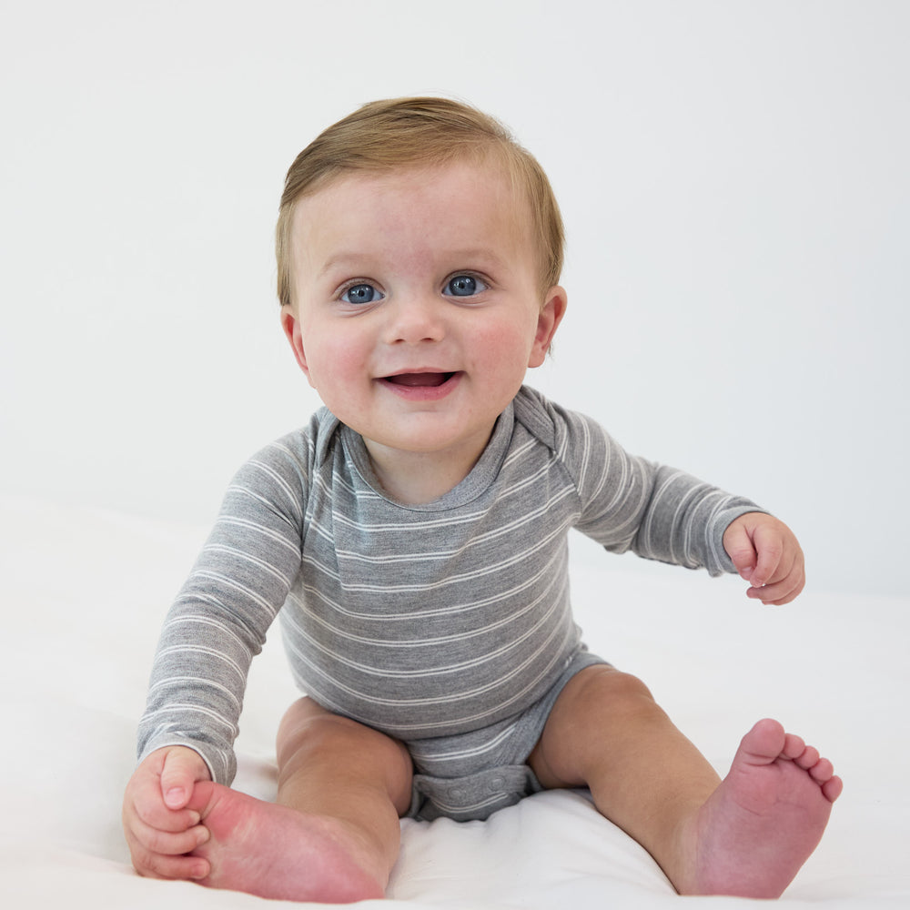 Smiling baby sitting down while in the Light Heather Gray Stripes Bodysuit