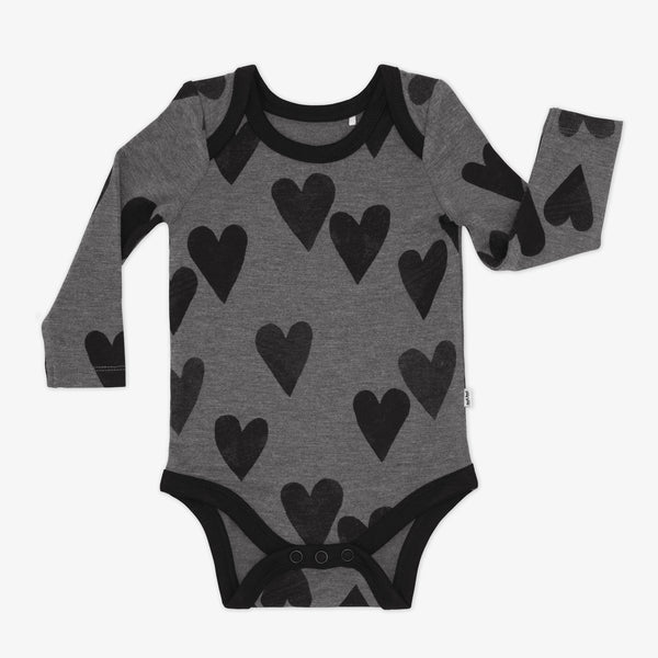 Flat lay of a Heather Hearts Bodysuit featuring long sleeves, a button snap closure on the bottom, and black hearts on a heather gray background