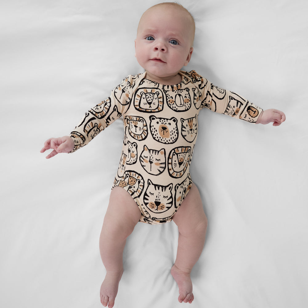 Infant lying down wearing a Lions, Tigers & Bears baby bodysuit featuring black and tan animal illustrations