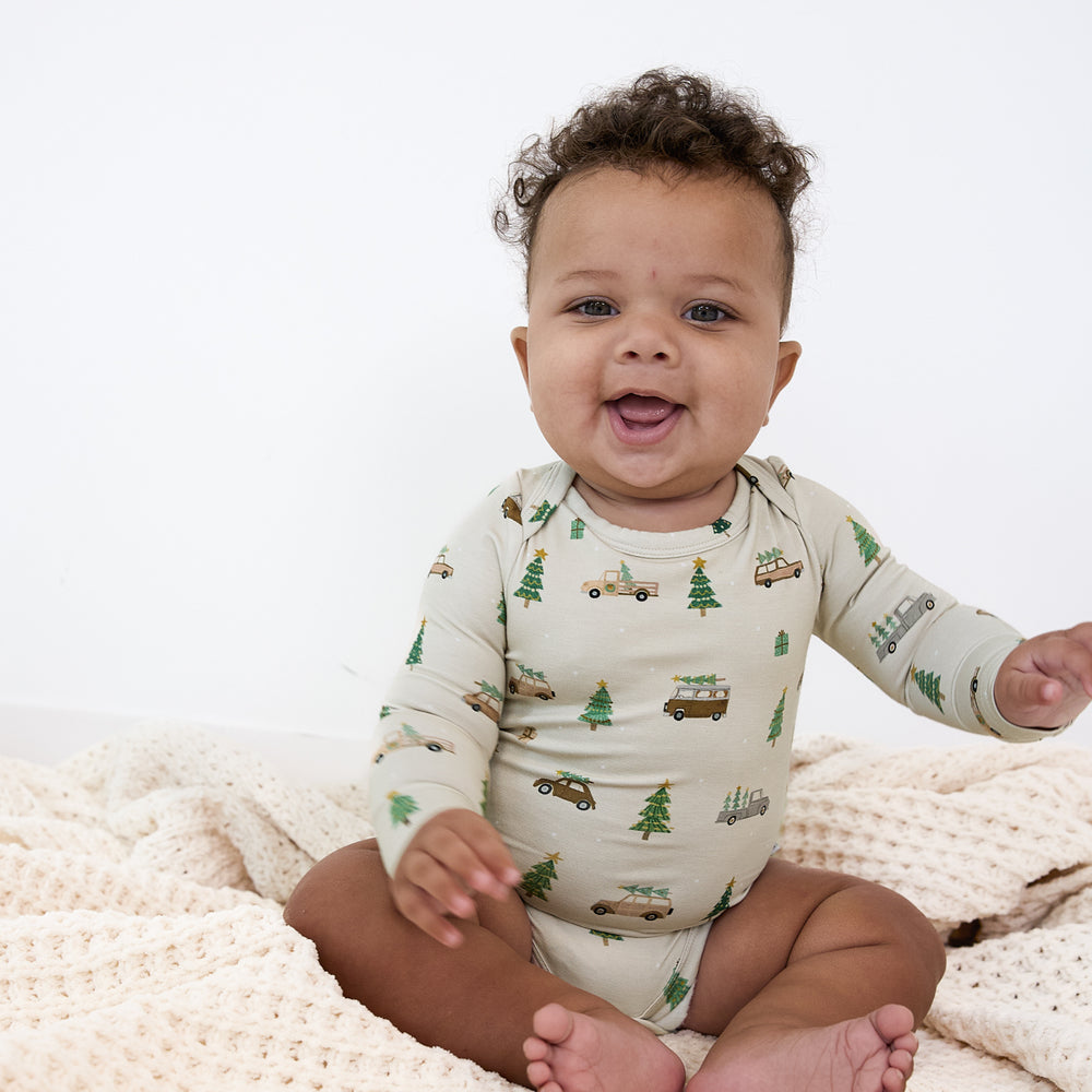 Image of a child sitting on a blanket wearing a Tree Traffic Bodysuit