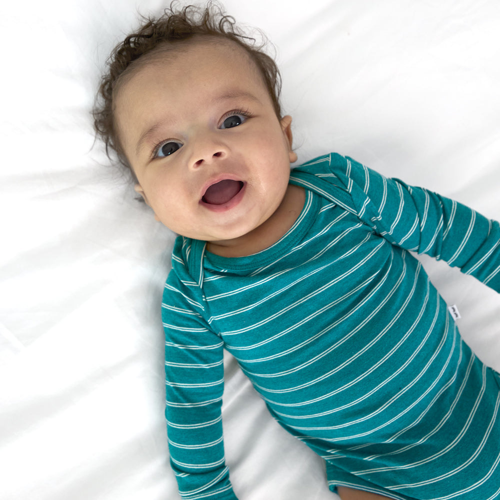 Top view close up image of baby laying down while wearing the Glacier Stripes Bodysuit