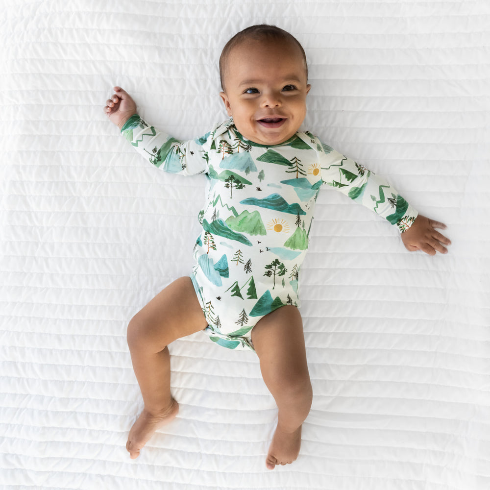 Image of a child laying on a blanket wearing a Mountain Mist Bodysuit