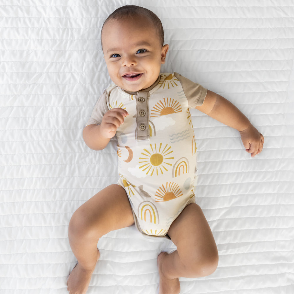 Image of an infant laying on a blanket wearing a Desert Sunrise Henley Bodysuit