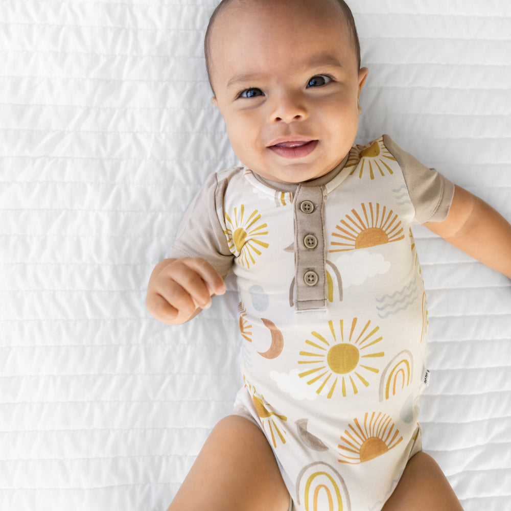 Close up image of an infant laying on a blanket wearing a Desert Sunrise Henley Bodysuit