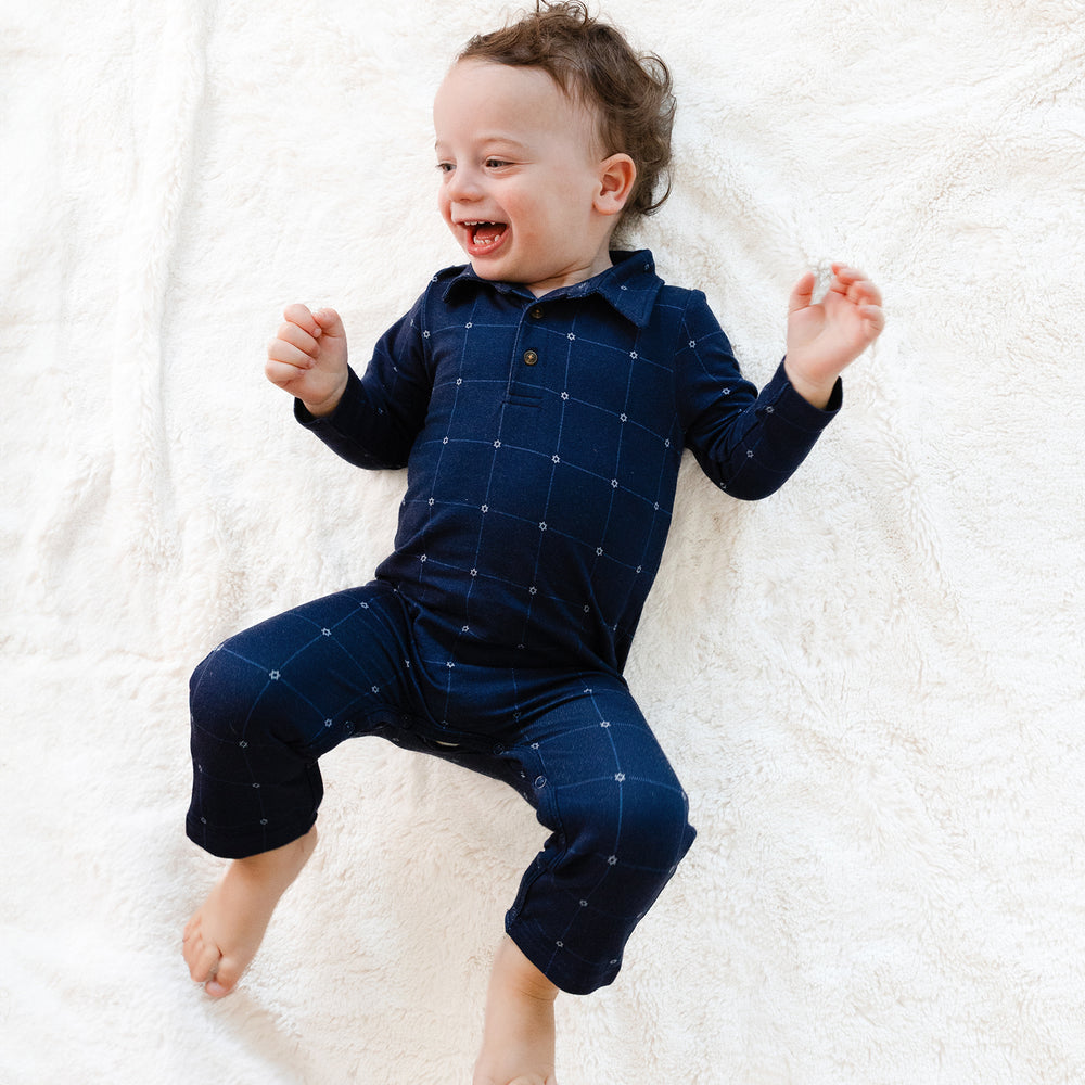 Child laying on a blanket wearing a Hanukkah Stars Plaid Polo Romper