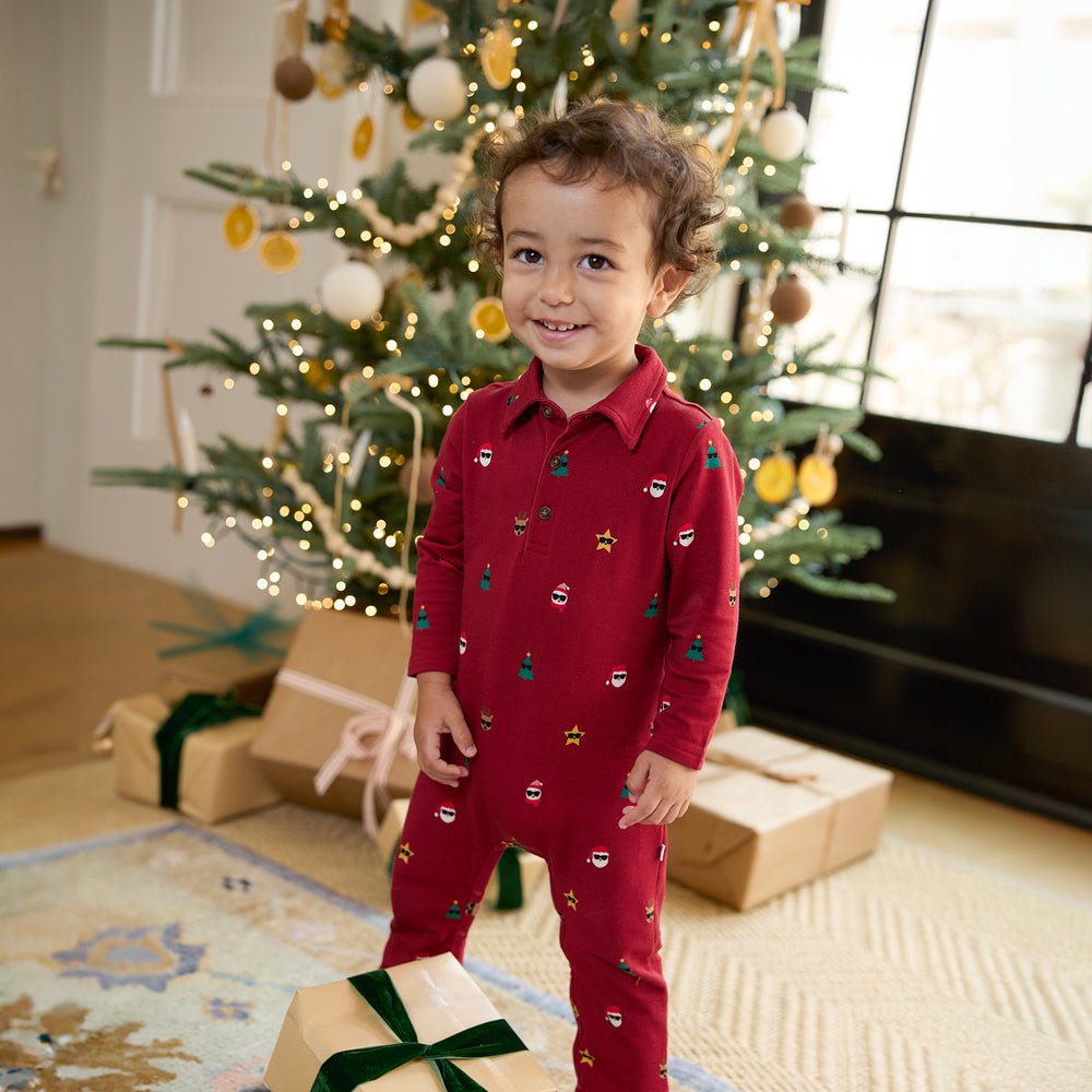 Image of a child standing in front of a Christmas tree wearing a Cool Christmas Polo Romper