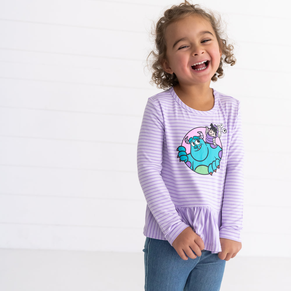 Smiling girl wearing the Disney Monsters, Inc. Peplum Tee 