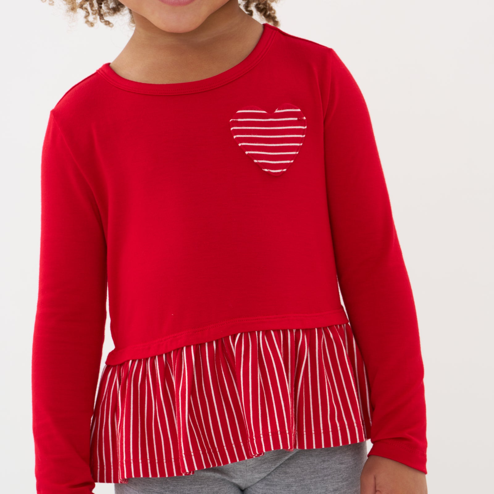 Close up image of a child wearing a Candy Red peplum tee