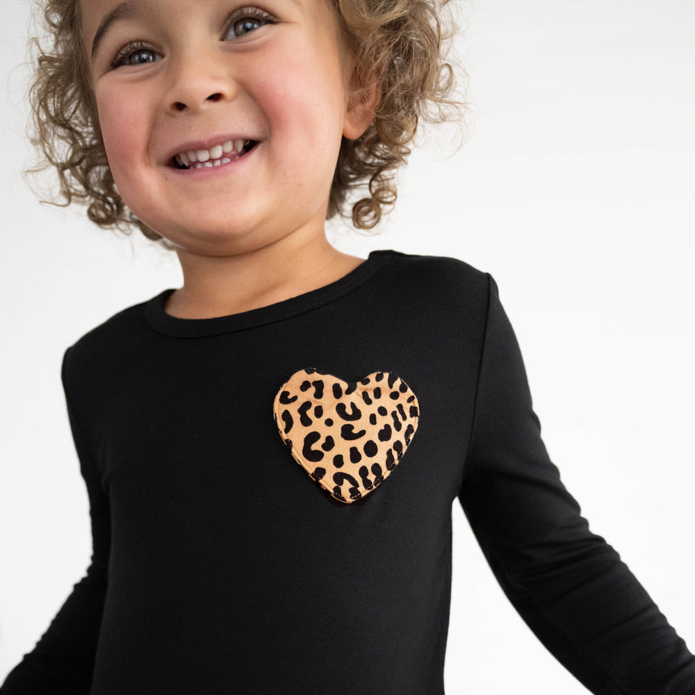 Close up image of girl wearing the Classic Leopard Pocket Peplum Tee and the heart pocket detail 