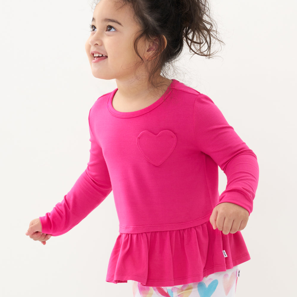 Click to see full screen - Close up image of a child wearing a Pink Punch peplum tee
