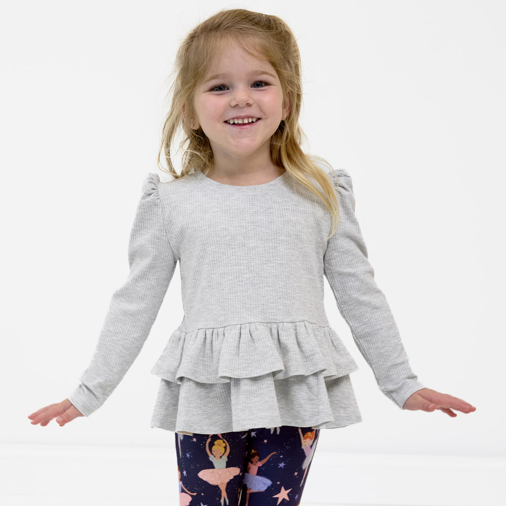 Smiling girl posing while wearing the Light Heather Gray Ribbed Tiered Peplum Top and the Twilight Ballet Leggings