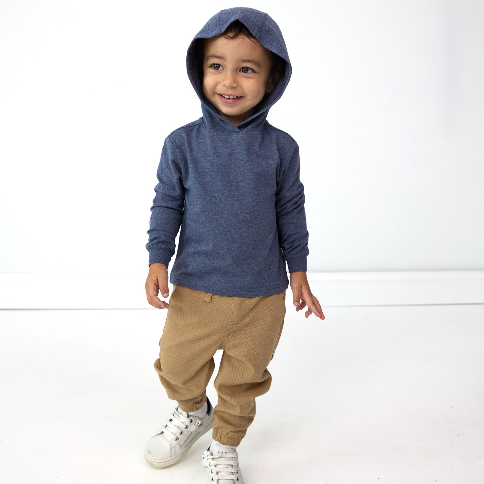 Smiling boy wearing the hood up on the Vintage Navy Relaxed Hooded Tee and the Toasted Hazelnut Denim Jogger