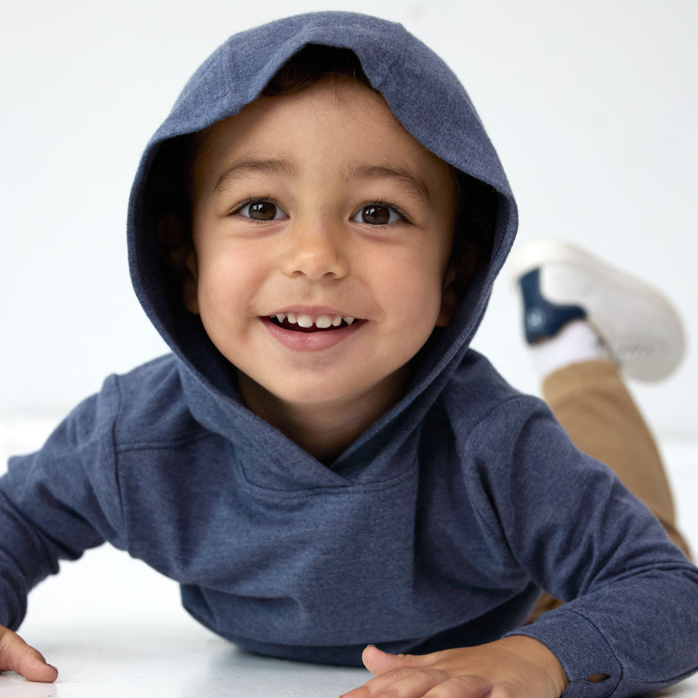 Close up image of boy smiling and laying on his stomach while displaying the hood detail on the Vintage Navy Relaxed Hooded Tee