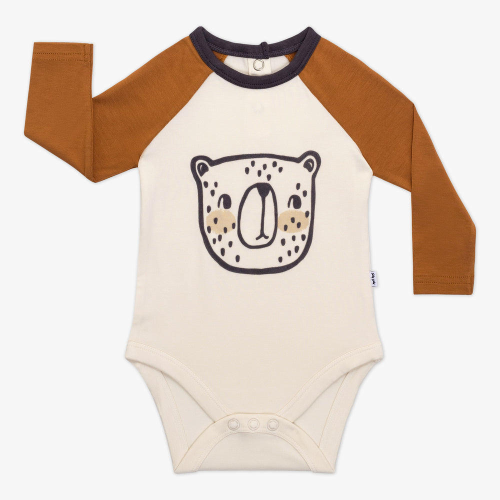 Flat lay of an Arctic Raglan baby bodysuit with tan long sleeves, a black bear illustration, and brown neckline