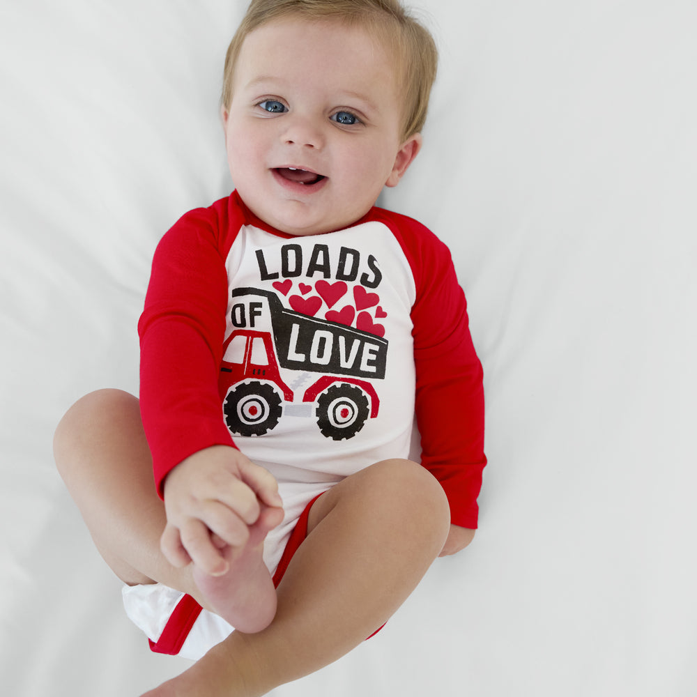 Infant lying on a blanket wearing a Loads of Love Raglan Bodysuit