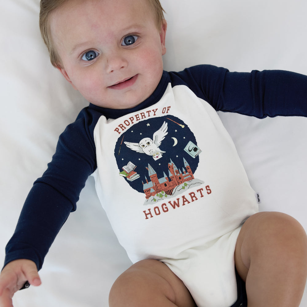 Close up image of an infant laying on a blanket wearing a Property of Hogwarts Raglan Bodysuit