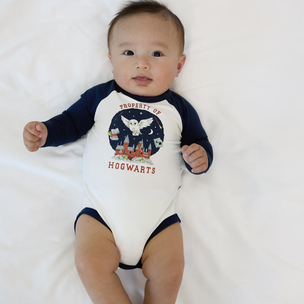 Image of an infant laying on a blanket wearing a Property of Hogwarts Raglan Bodysuit