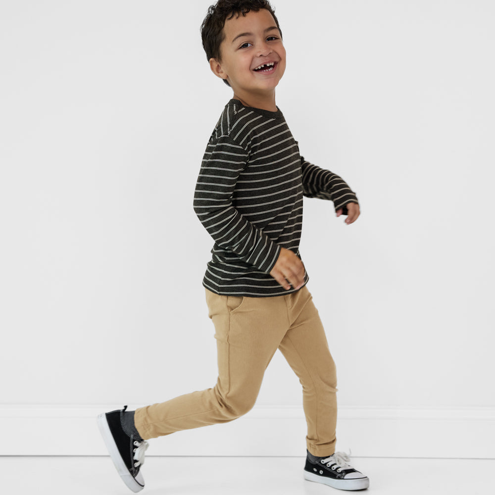 Running child wearing a Heather Black Stripes relaxed pocket tee paired with tan denim joggers