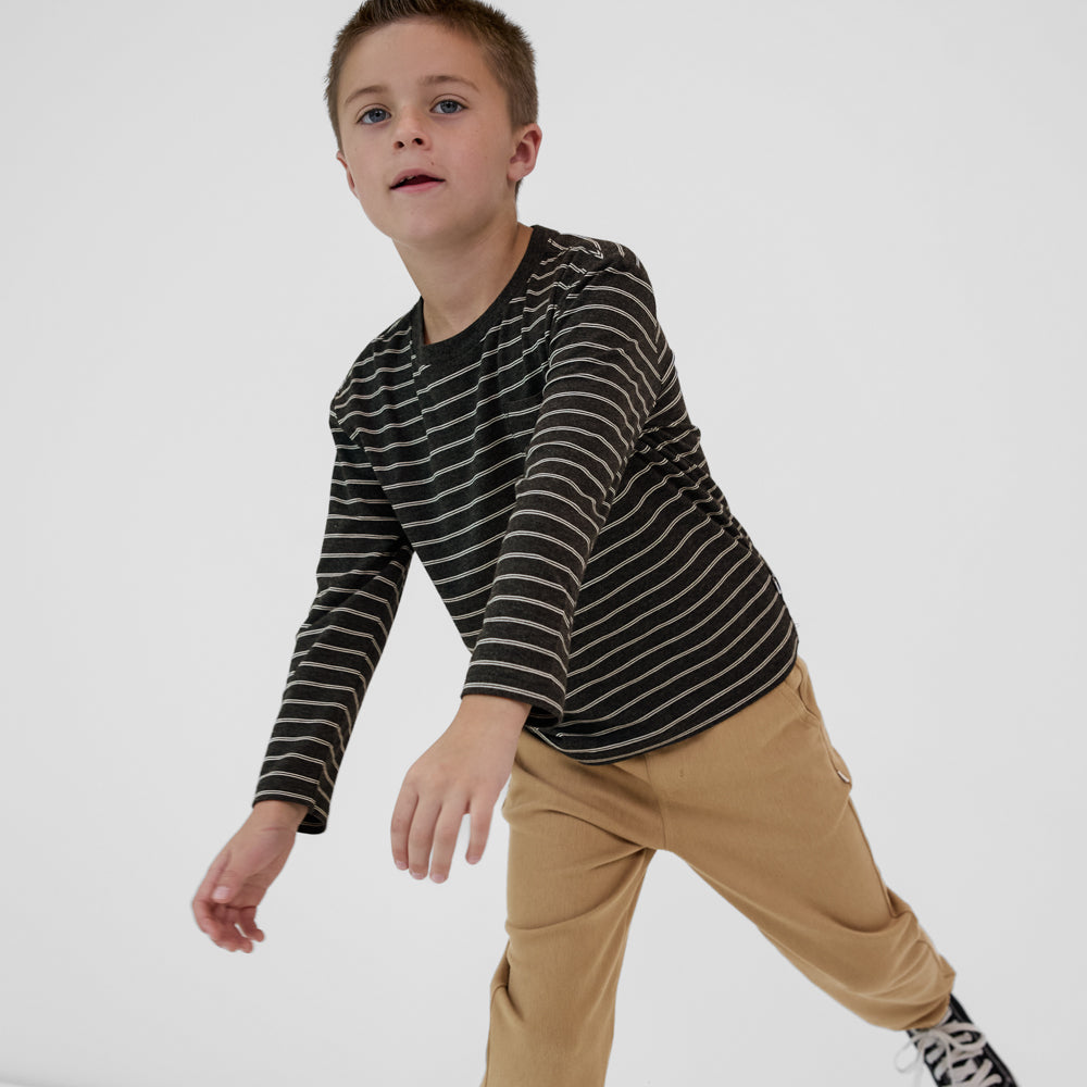 Child wearing a Heather Black Stripes long sleeve relaxed pocket tee paired with tan denim joggers