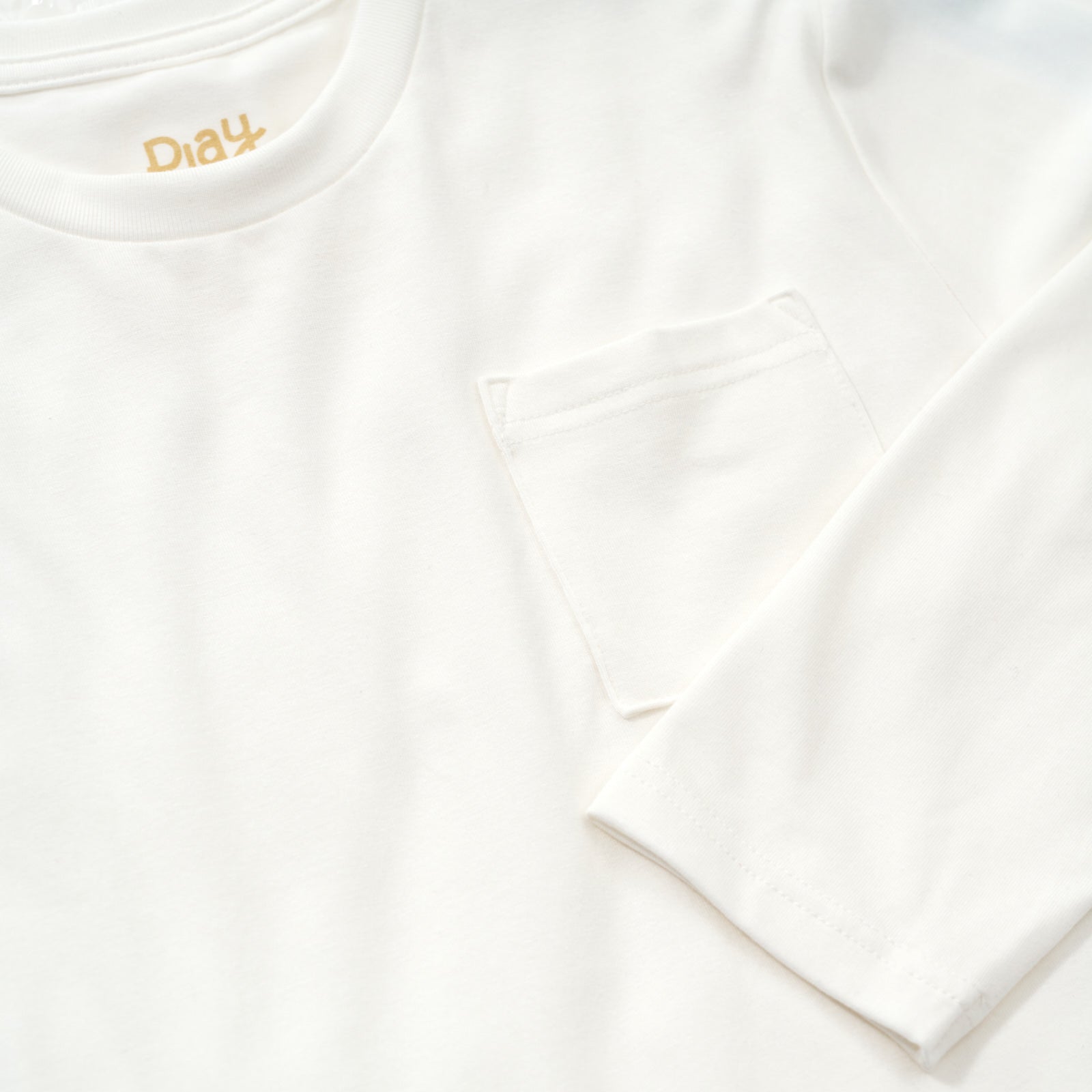 Close up image of the collar, sleeve and pocket detail on the Soft White Long Sleeve Relaxed Pocket Tee