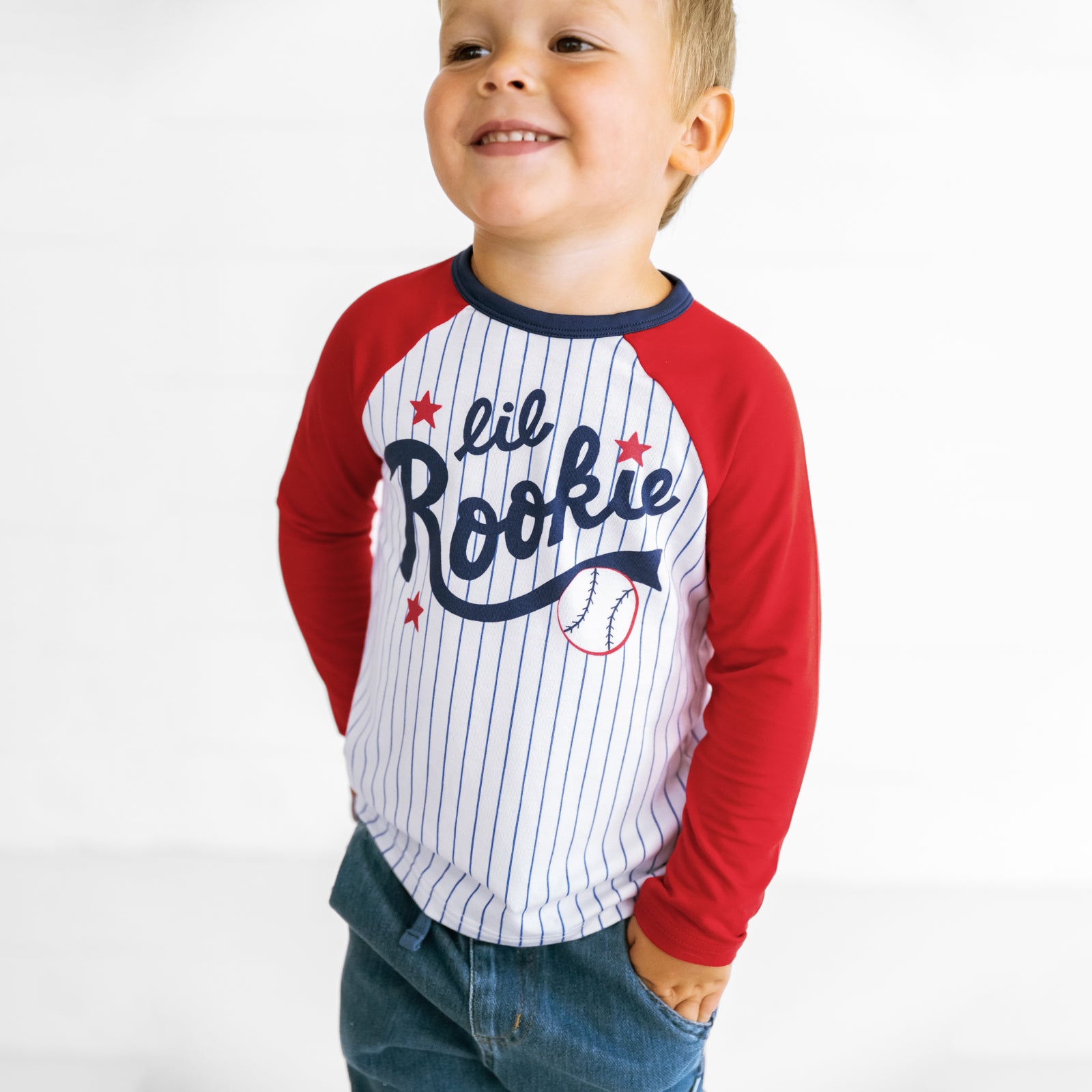 Close up image of a child wearing a Blue Lil Rookie Raglan Tee and Midwash Blue Denim Jogger