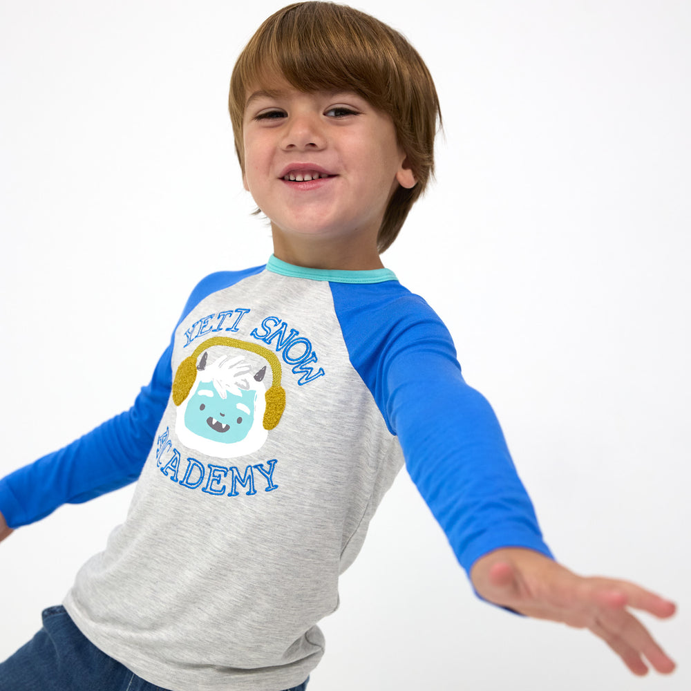 Smiling boy posing while wearing the Yeti Snow Academy Raglan Tee