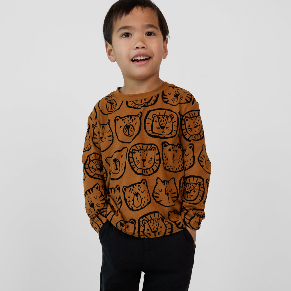 Child wearing an Amber Lions, Tigers & Bears Relaxed Tee with black animal illustrations, paired with black joggers.