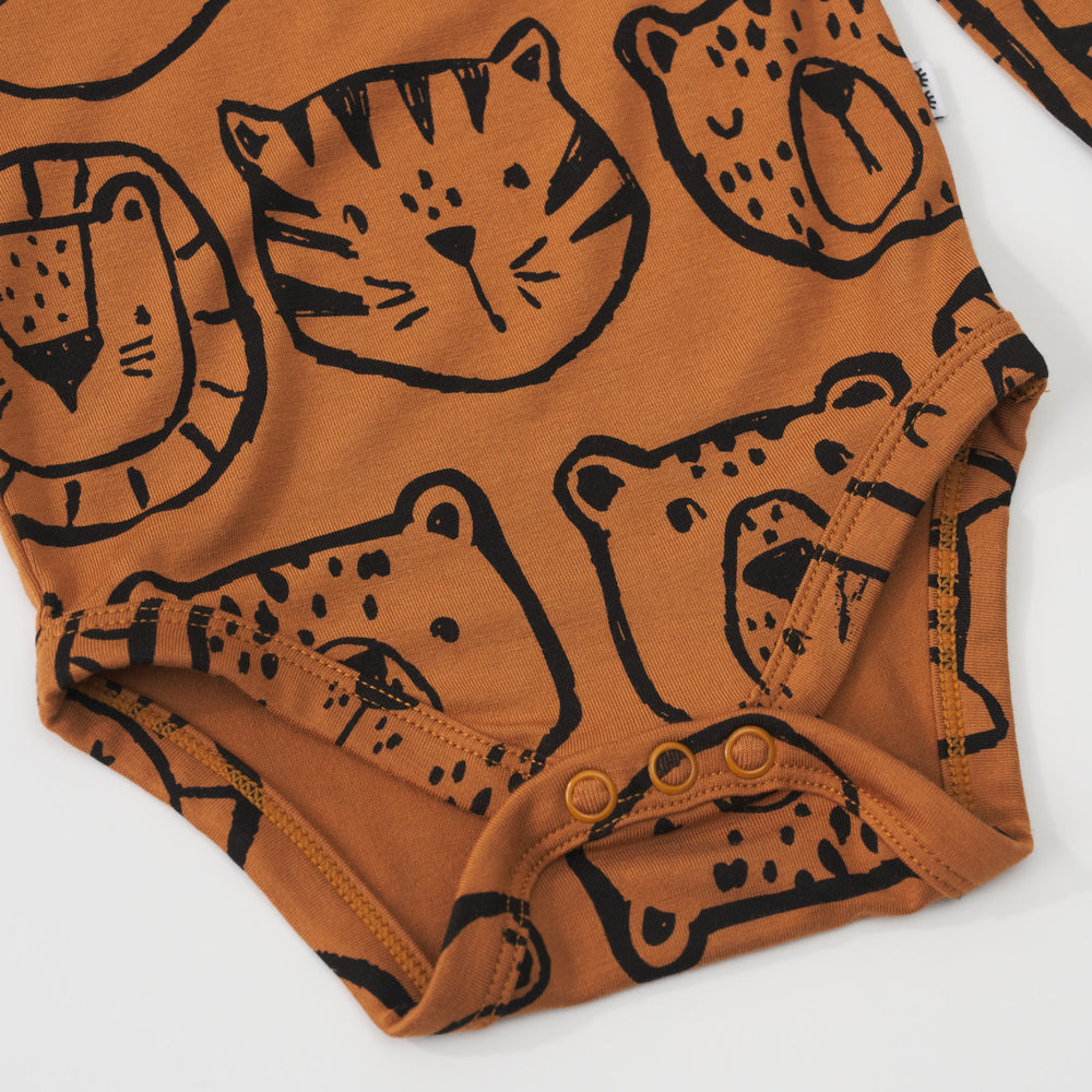 Close-up view of the bottom snap closures on an Amber Lions, Tigers & Bears baby bodysuit with black animal illustrations.