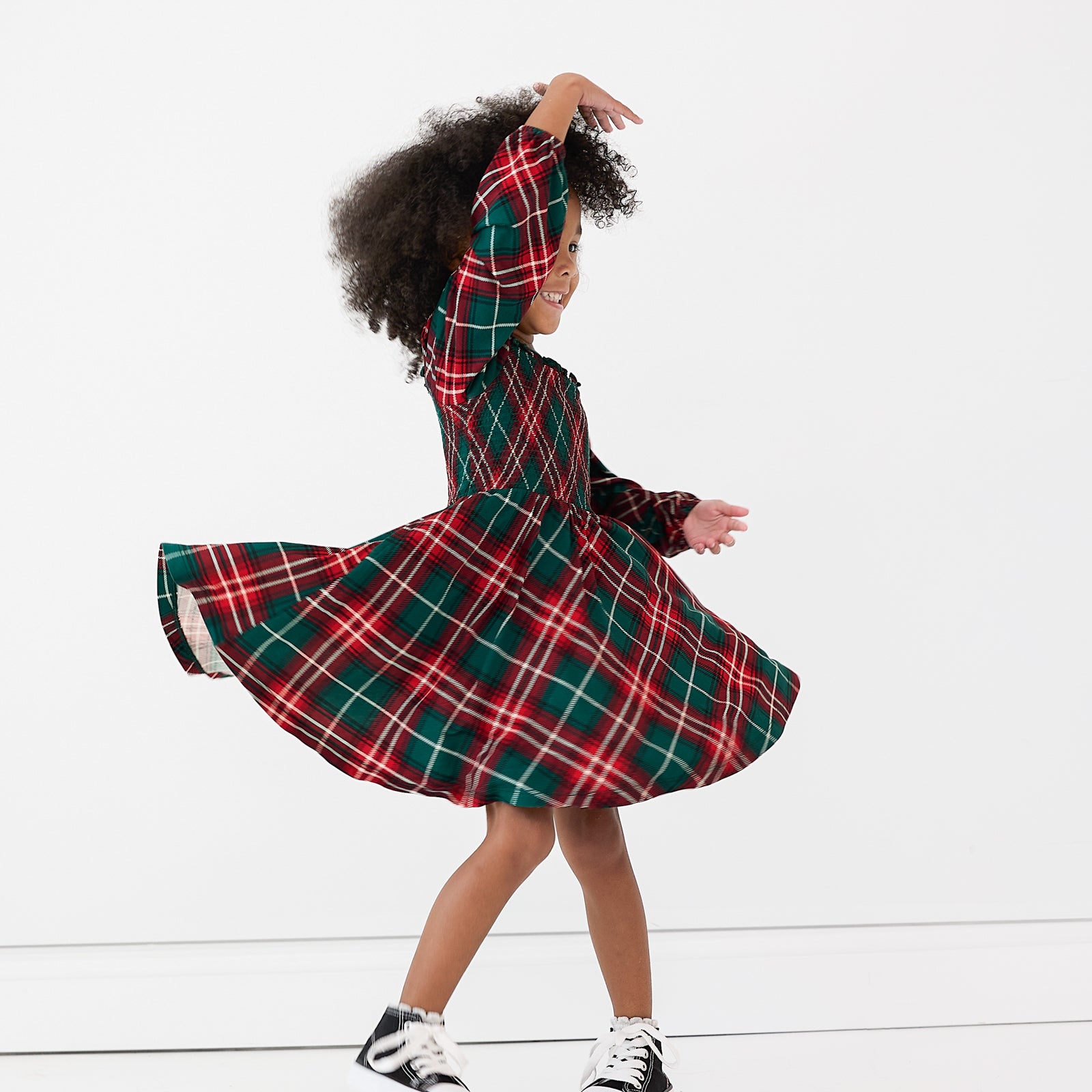 Image of a girl spinning around in a Fireside Plaid Smocked Dress