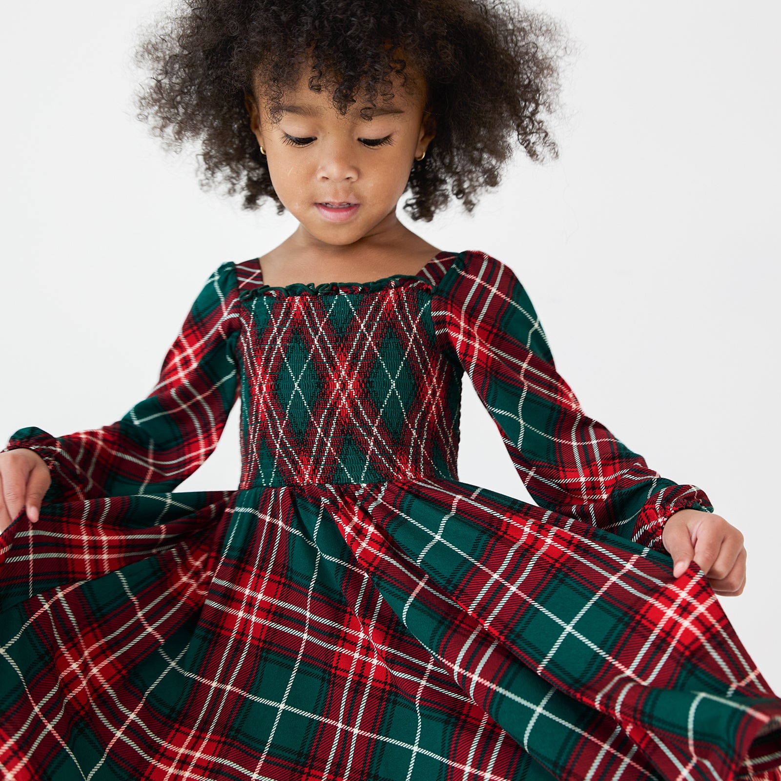 Close up image of a girl wearing a Fireside Plaid Smocked Dress