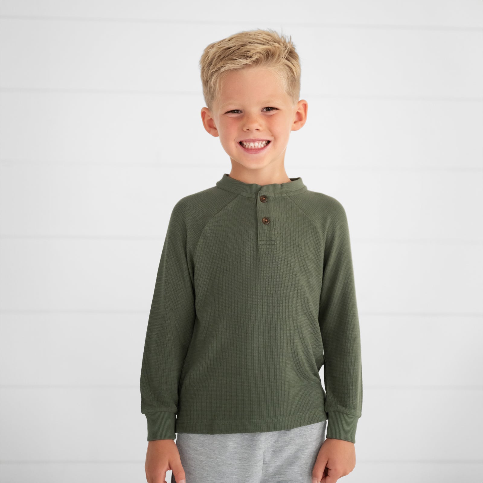 Close up image of a child wearing an Olive Waffle Henley Tee and Light Heather Gray Jogger